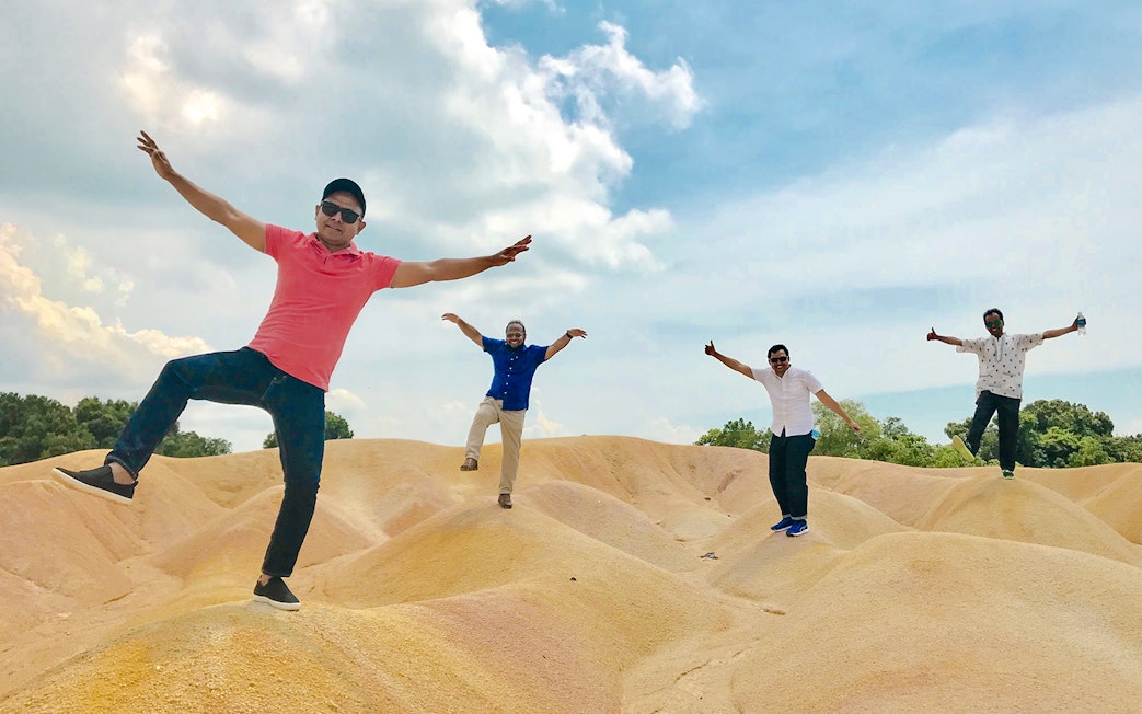 Tourists posing playfully on sand dunes at Bintan Mini Desert.