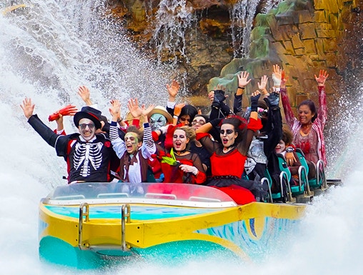 Visitors in costumes enjoying a water ride at Gardaland Park.