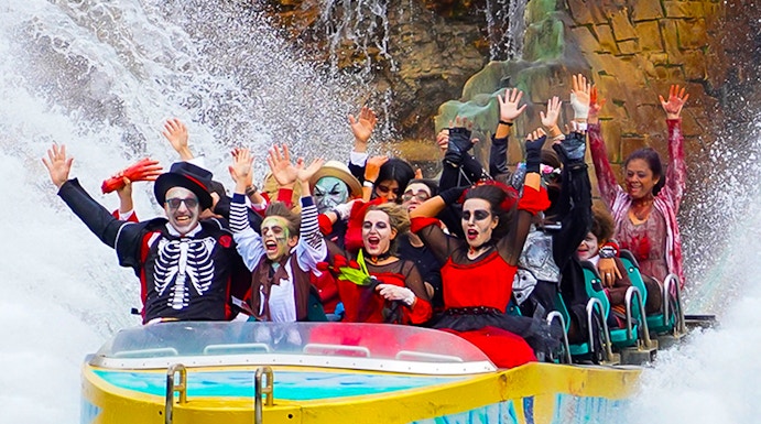 Visitors in costumes enjoying a water ride at Gardaland Park.