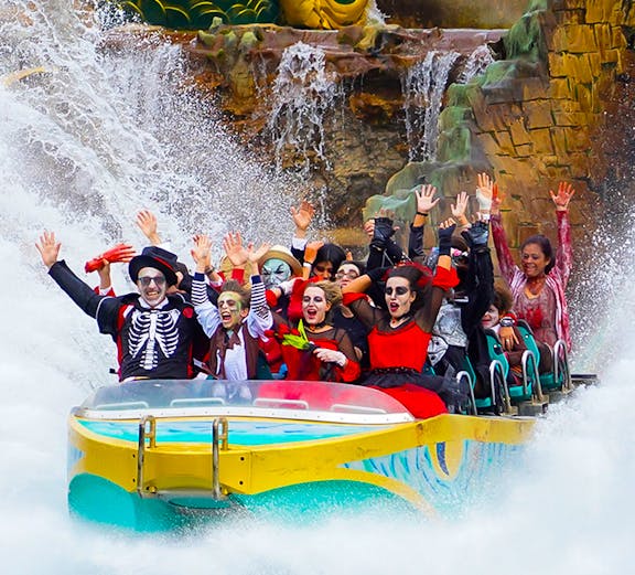 Visitors in costumes enjoying a water ride at Gardaland Park.