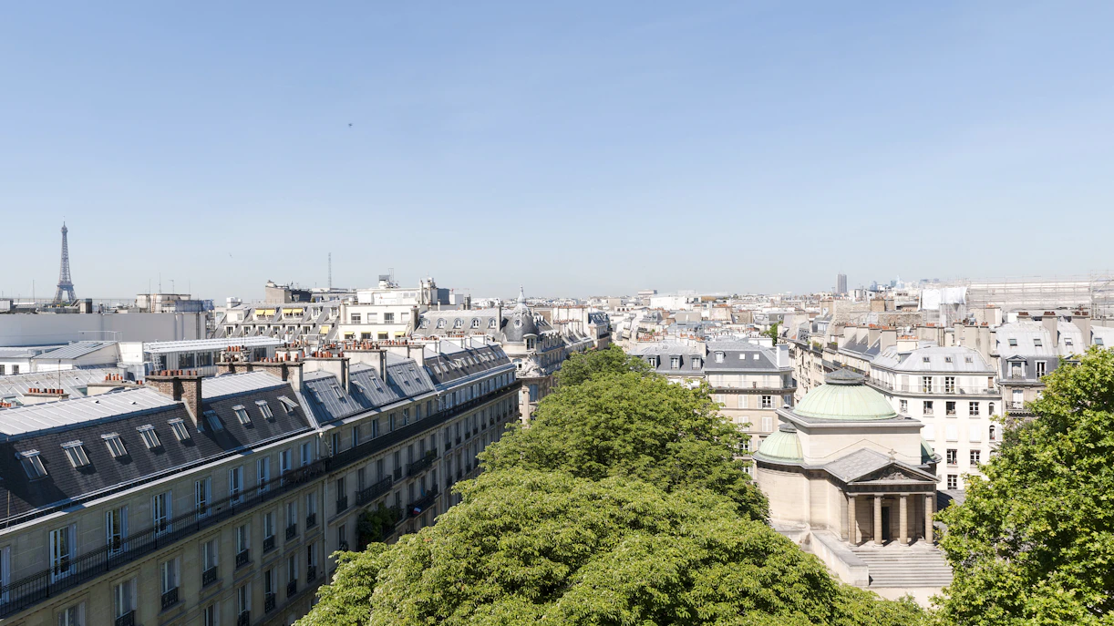 View of Paris rooftops with Expiatory Chapel and Eiffel Tower in the distance.