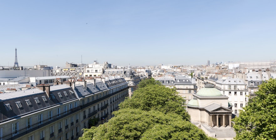 View of Paris rooftops with Expiatory Chapel and Eiffel Tower in the distance.