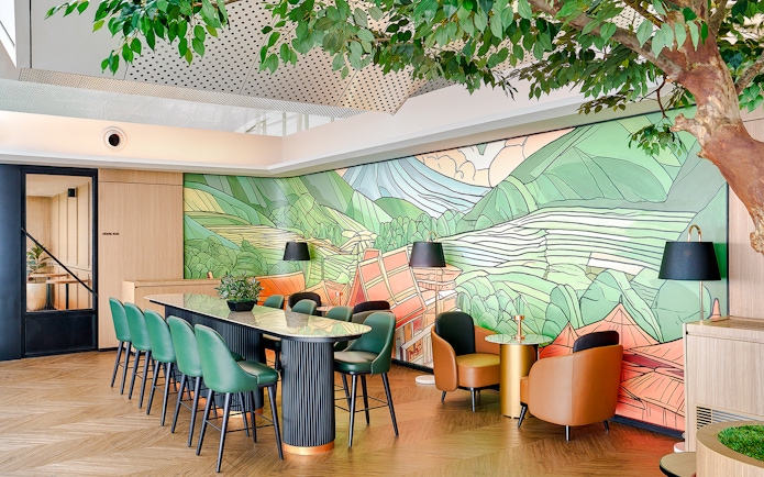 Lounge interior with green chairs, mural of mountains, and potted plants.