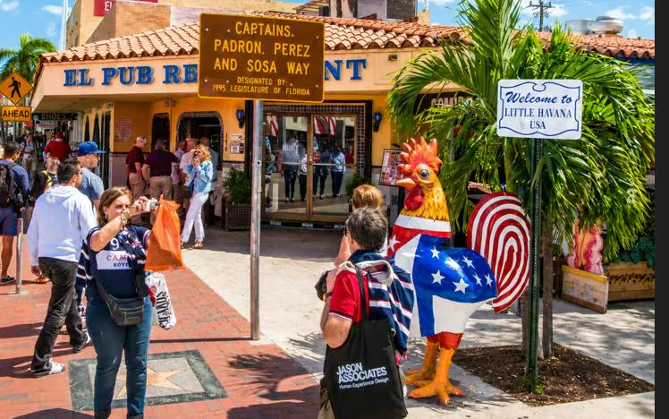Little Havana street scene with tourists, colorful rooster statue, and El Pub Restaurant in Miami.