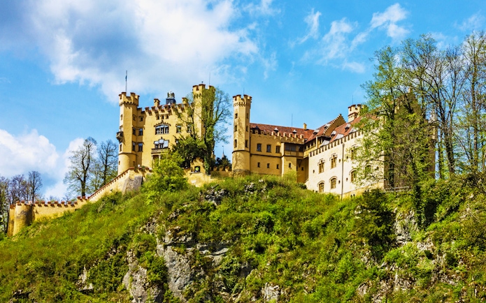 Hohenschwangau Castle on a hill surrounded by trees, Bavaria, Germany.