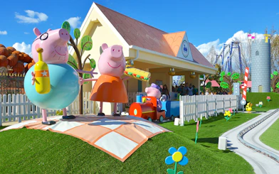 Peppa Pig characters at Gardaland Park attraction with colorful scenery.