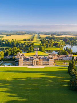 Aerial view of Blenheim Palace with expansive gardens and surrounding countryside in Oxfordshire, England.