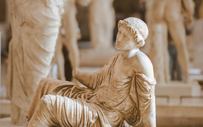 Seated ancient statue in the Louvre Museum, Paris, France.