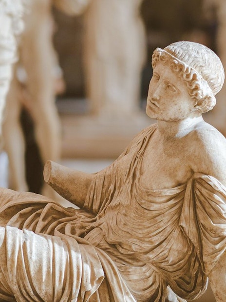 Seated ancient statue in the Louvre Museum, Paris, France.