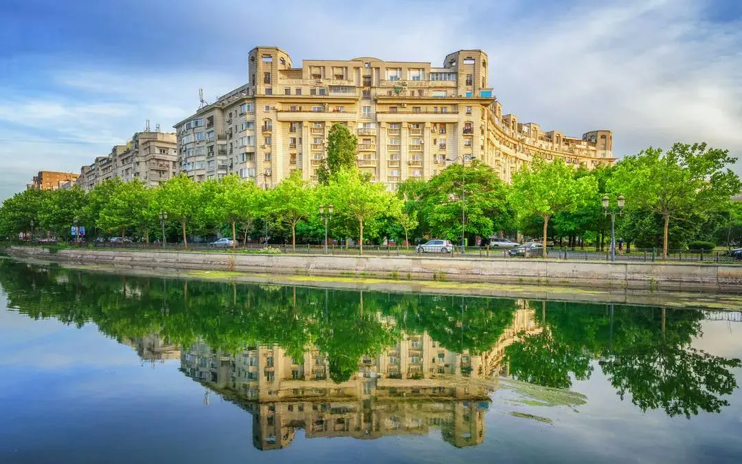 Apartment buildings reflected in a canal at Văcărești Nature Park, Bucharest.