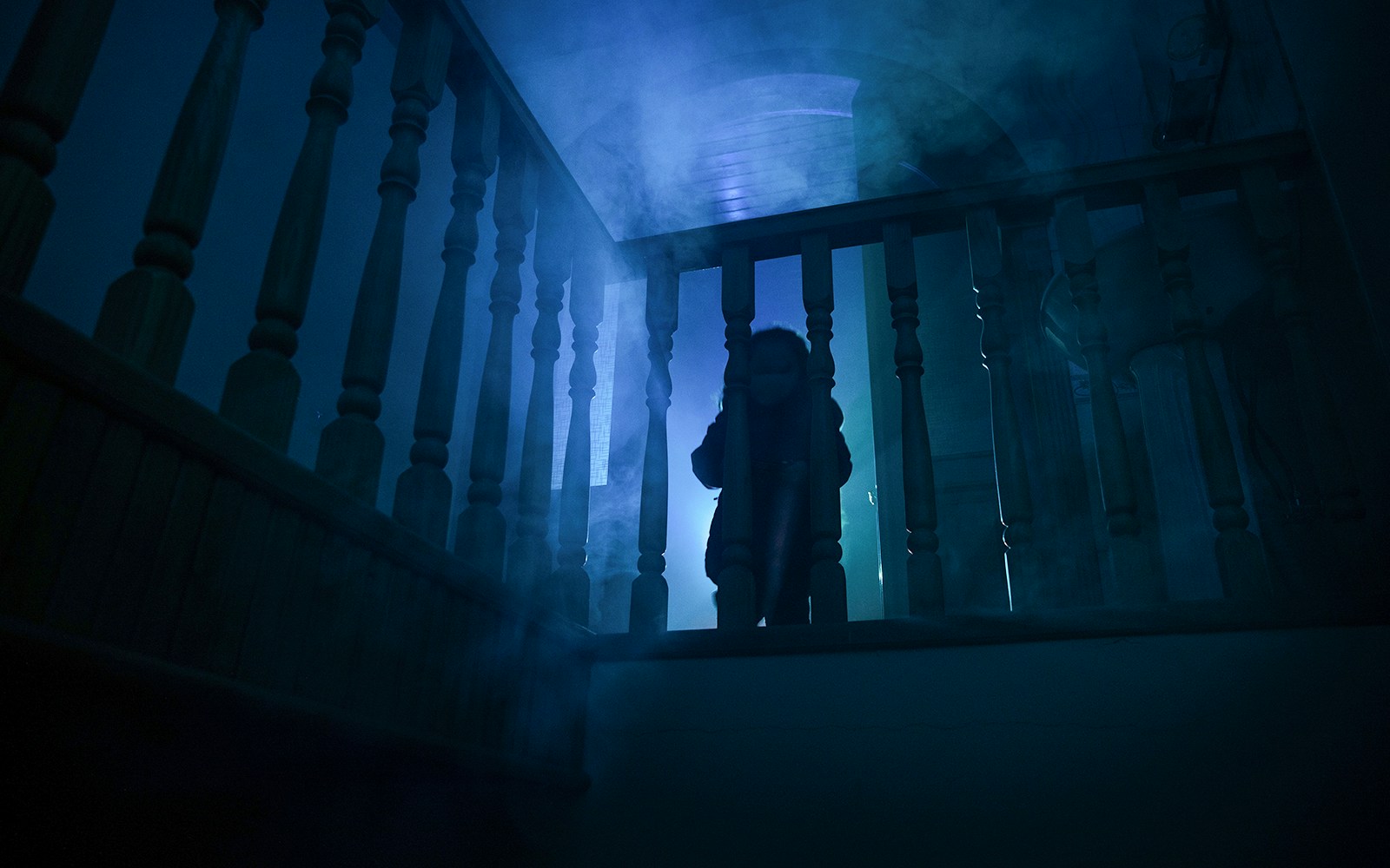 Child in eerie lighting on staircase at haunted halloween house