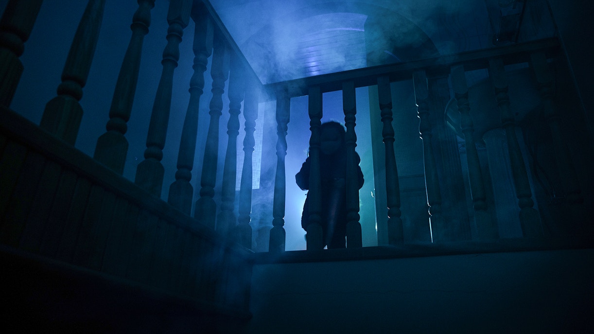 Child in eerie lighting on staircase at Harrowing Halloween 3, Singapore Discovery Centre haunted house.