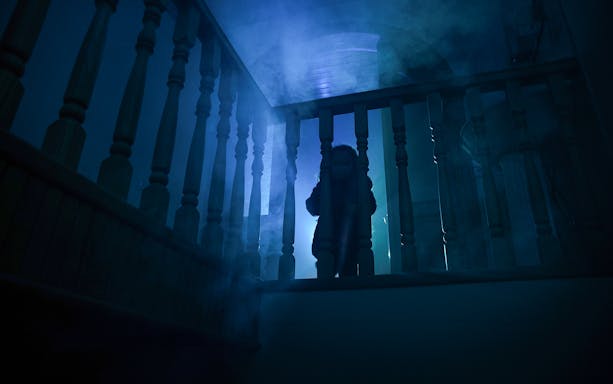 Child in eerie lighting on staircase at Harrowing Halloween 3, Singapore Discovery Centre haunted house.