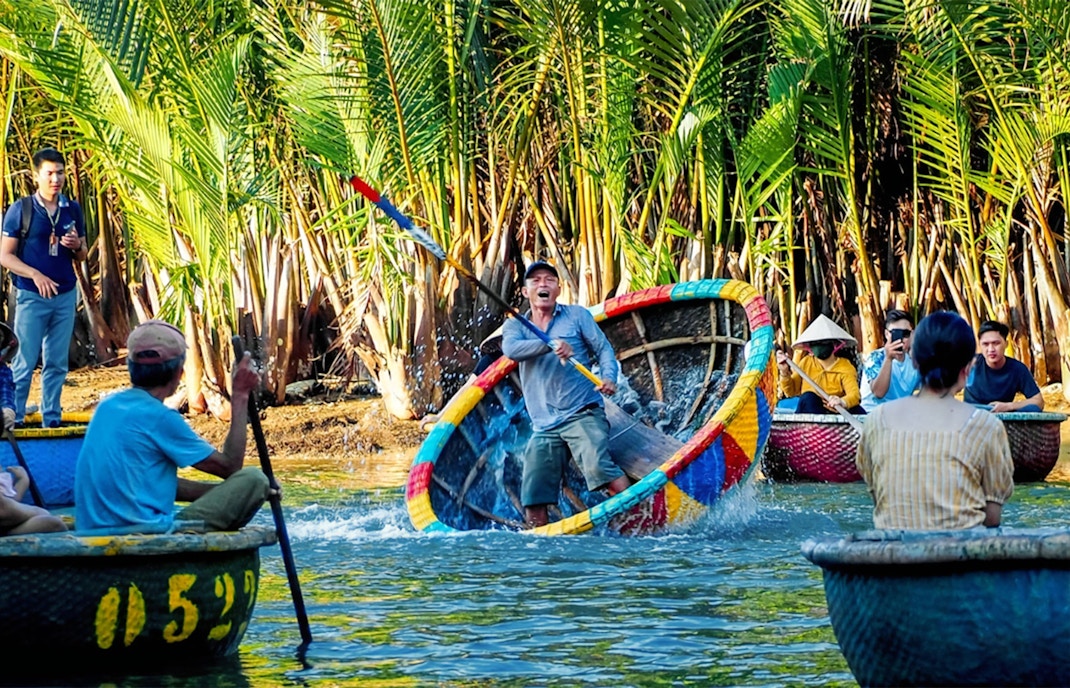People enjoying a vibrant coconut basket boat ride through lush palm trees in Vietnam.