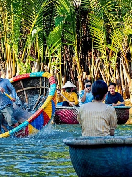 People enjoying a vibrant coconut basket boat ride through lush palm trees in Vietnam.