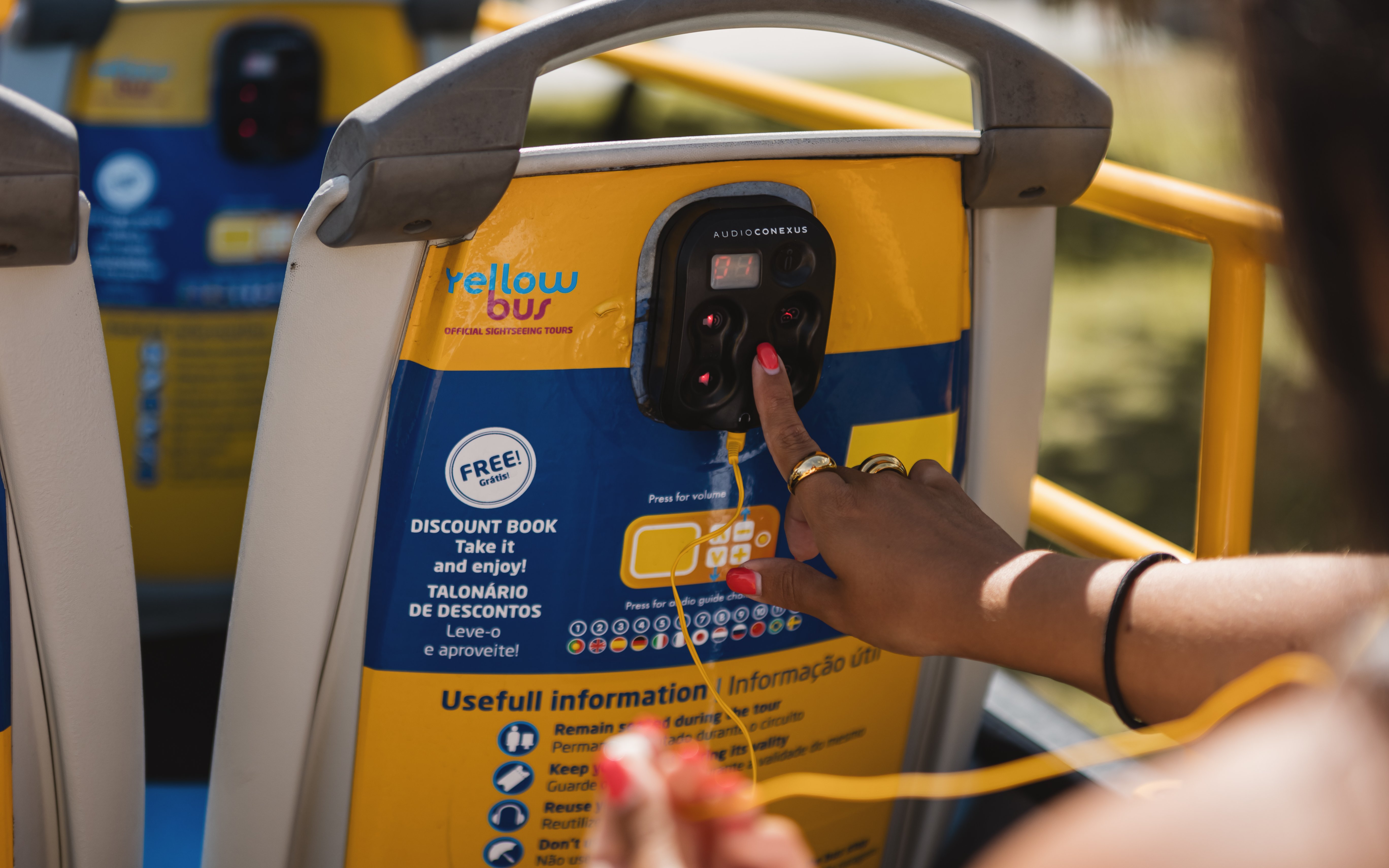 Tourist using audio guide on Yellow Bus during Lisbon Hop-on Hop-off Bus Tour.