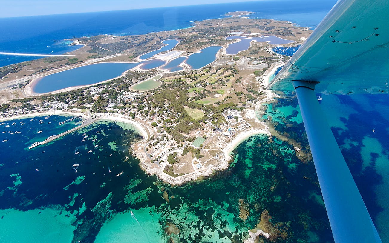Aerial view of Rottnest Island's coastline and salt lakes, featuring turquoise waters.