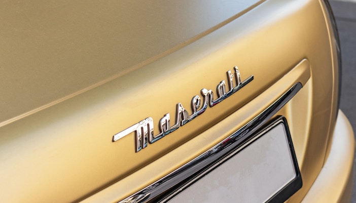 Maserati logo on a gold car in showroom.