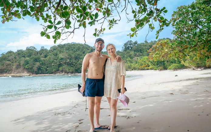 Couple enjoying the beach at Manuel Antonio National Park with lush forest backdrop.