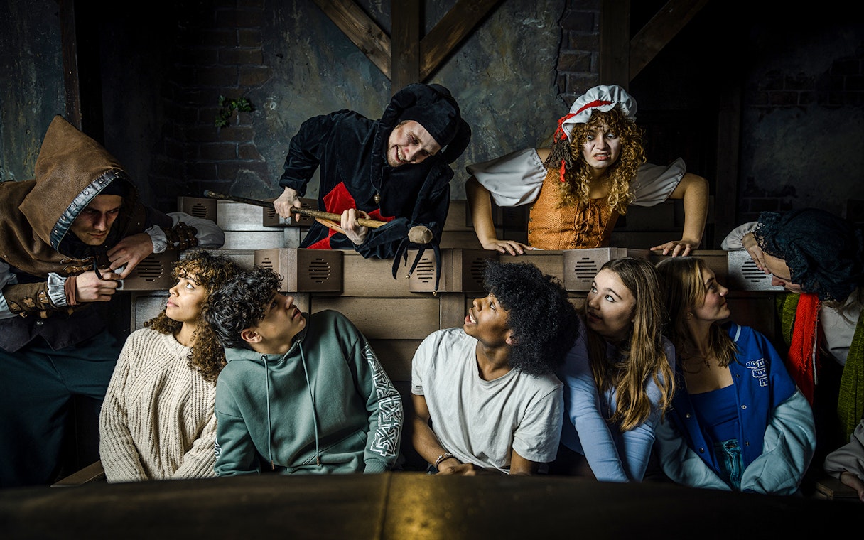 Guests interacting with actors in medieval costumes at the Amsterdam Dungeon.