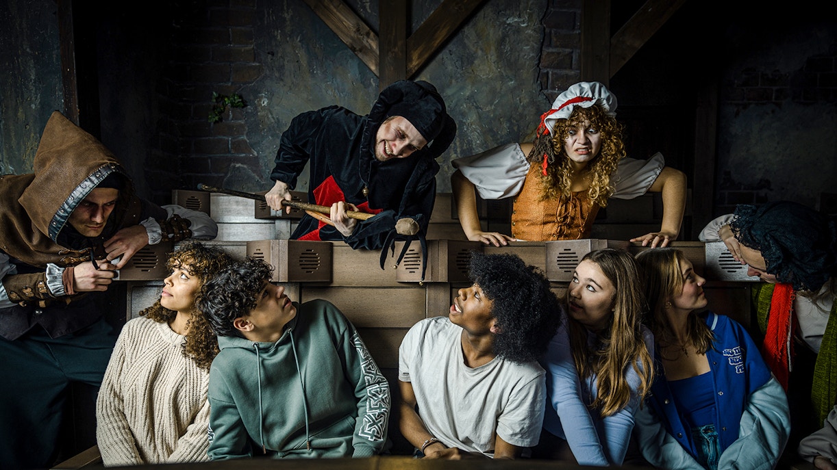 Guests interacting with actors in medieval costumes at the Amsterdam Dungeon.
