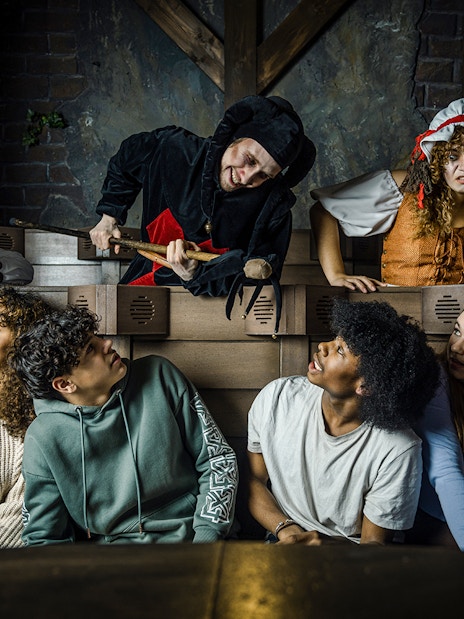 Guests interacting with actors in medieval costumes at the Amsterdam Dungeon.