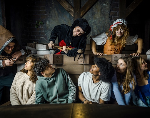 Guests interacting with actors in medieval costumes at the Amsterdam Dungeon.