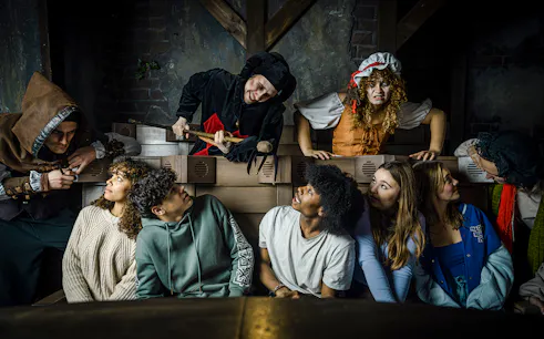 Guests interacting with actors in medieval costumes at the Amsterdam Dungeon.