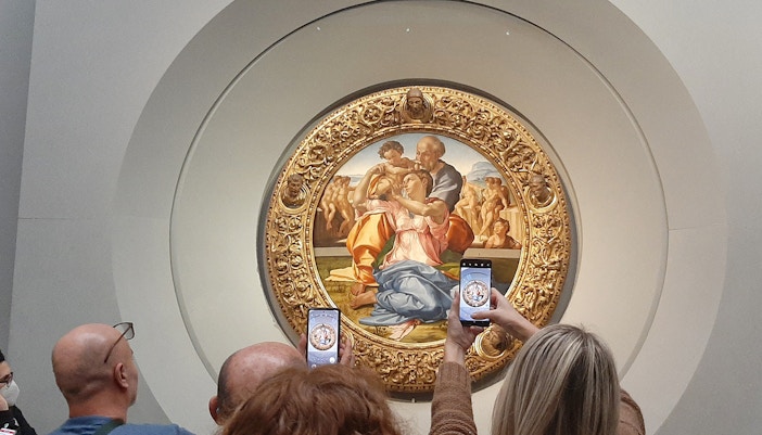 Holy Family by Michelangelo painting in Uffizi Gallery, Florence, Italy with visitors using audio guides.