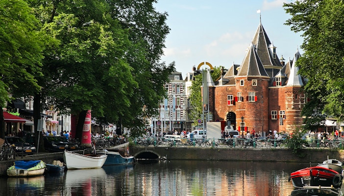 Kloveniersburgwal canal with boats and historic building in Amsterdam.