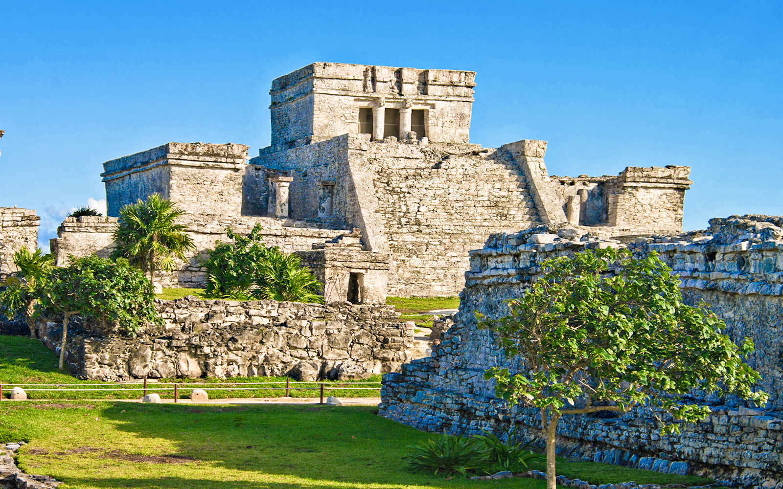Ancient stone structures of the Mayan city of Tulum, Mexico, with clear blue sky.