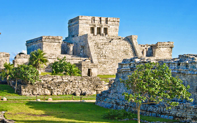 Ancient stone structures of the Mayan city of Tulum, Mexico, with clear blue sky.