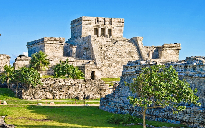 Ancient stone structures of the Mayan city of Tulum, Mexico, with clear blue sky.