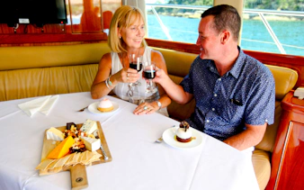 Couple enjoying wine and dessert on Sydney Harbour sightseeing cruise.