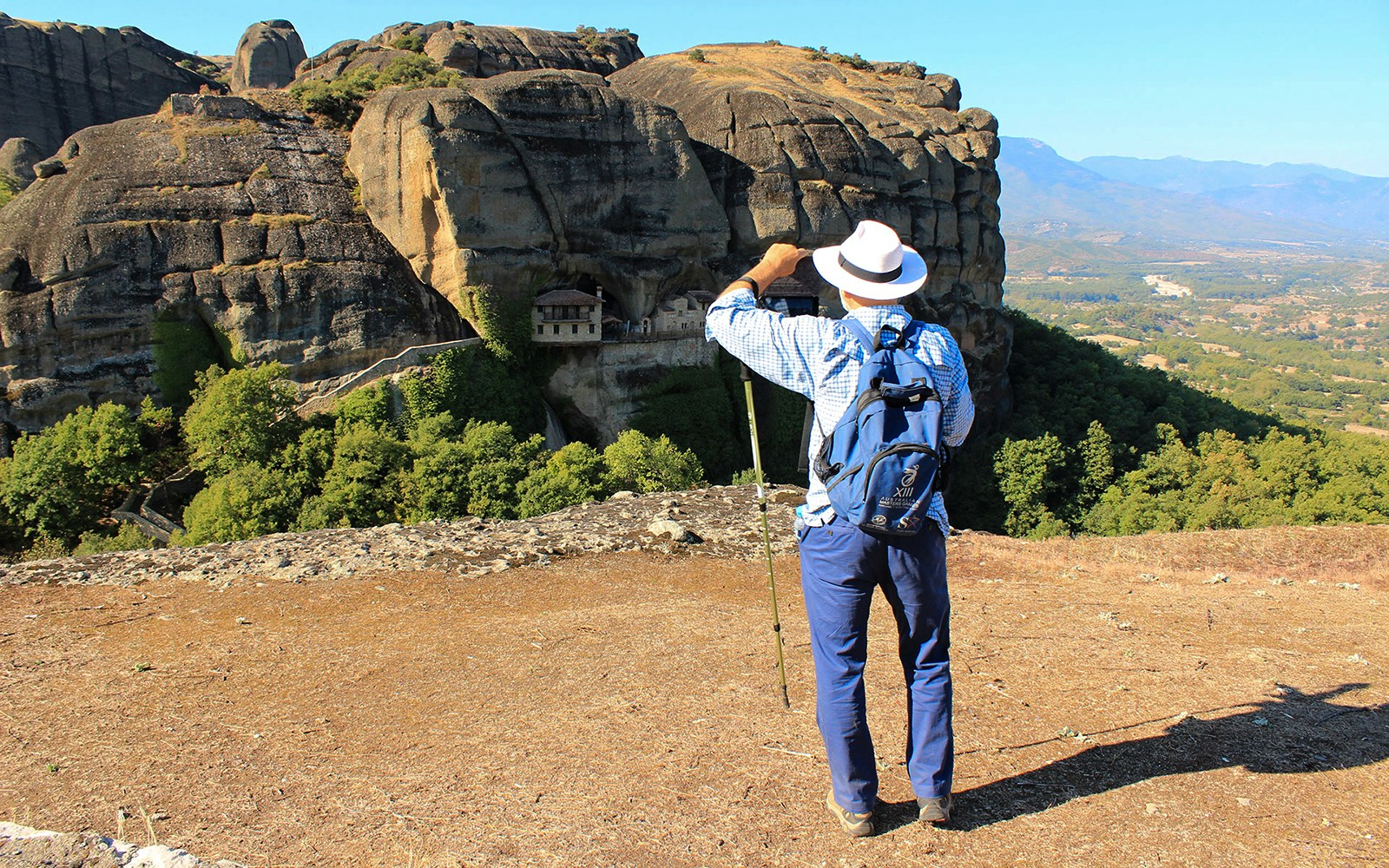 Guest hiking with view of Meteora rock formations and monastery in Greece.