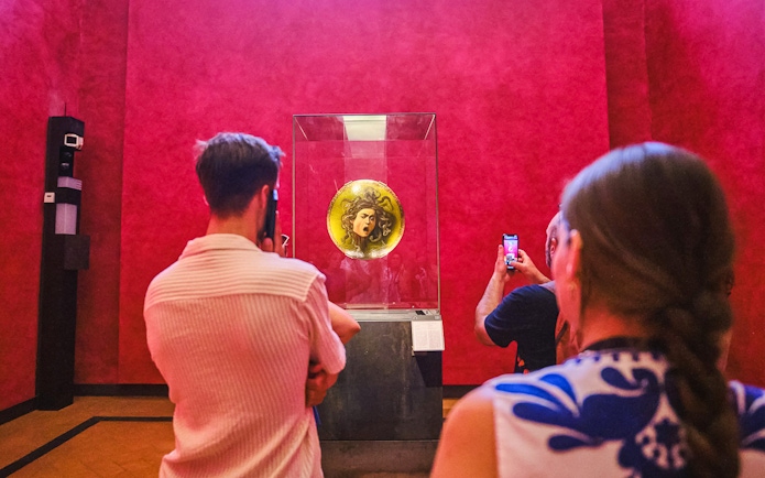 Visitors viewing Medusa shield at Uffizi Gallery during private Vasari Corridor tour.