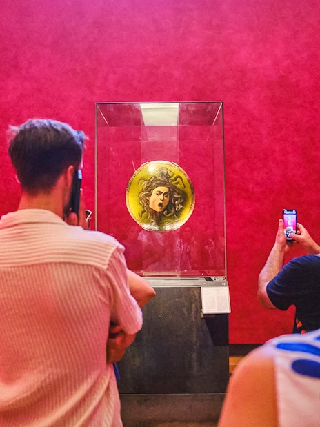 Visitors viewing Medusa shield at Uffizi Gallery during private Vasari Corridor tour.
