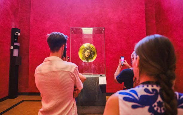 Visitors viewing Medusa shield at Uffizi Gallery during private Vasari Corridor tour.