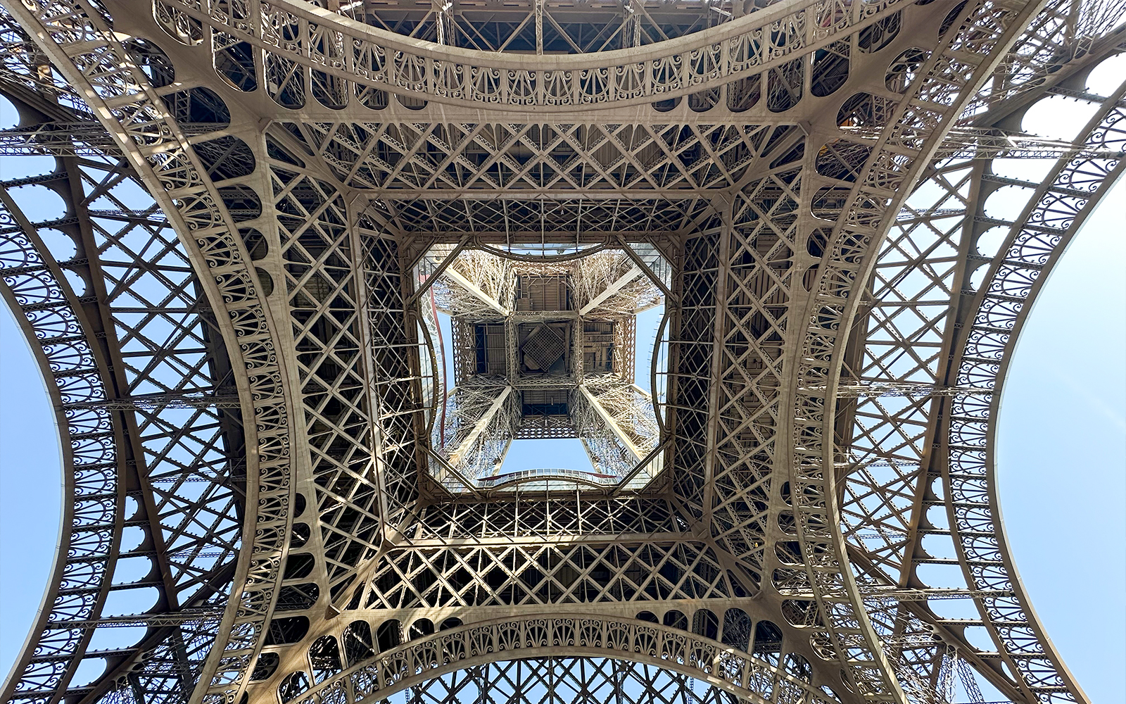View from beneath the Eiffel Tower's intricate iron lattice structure in Paris.
