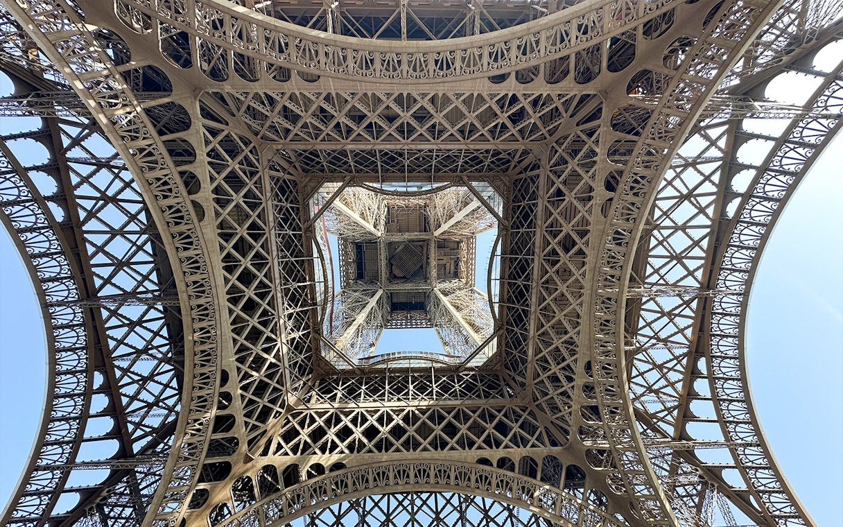 View from beneath the Eiffel Tower's intricate iron lattice structure in Paris.