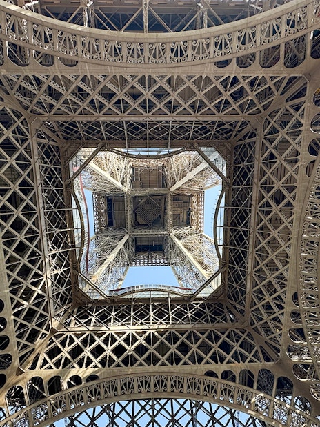 View from beneath the Eiffel Tower's intricate iron lattice structure in Paris.