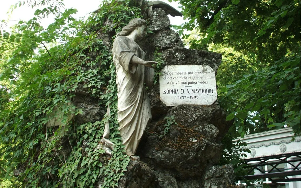 Statue and gravestone of Sophia D. A. Mavrodin at Bellu Cemetery, Bucharest, surrounded by greenery.