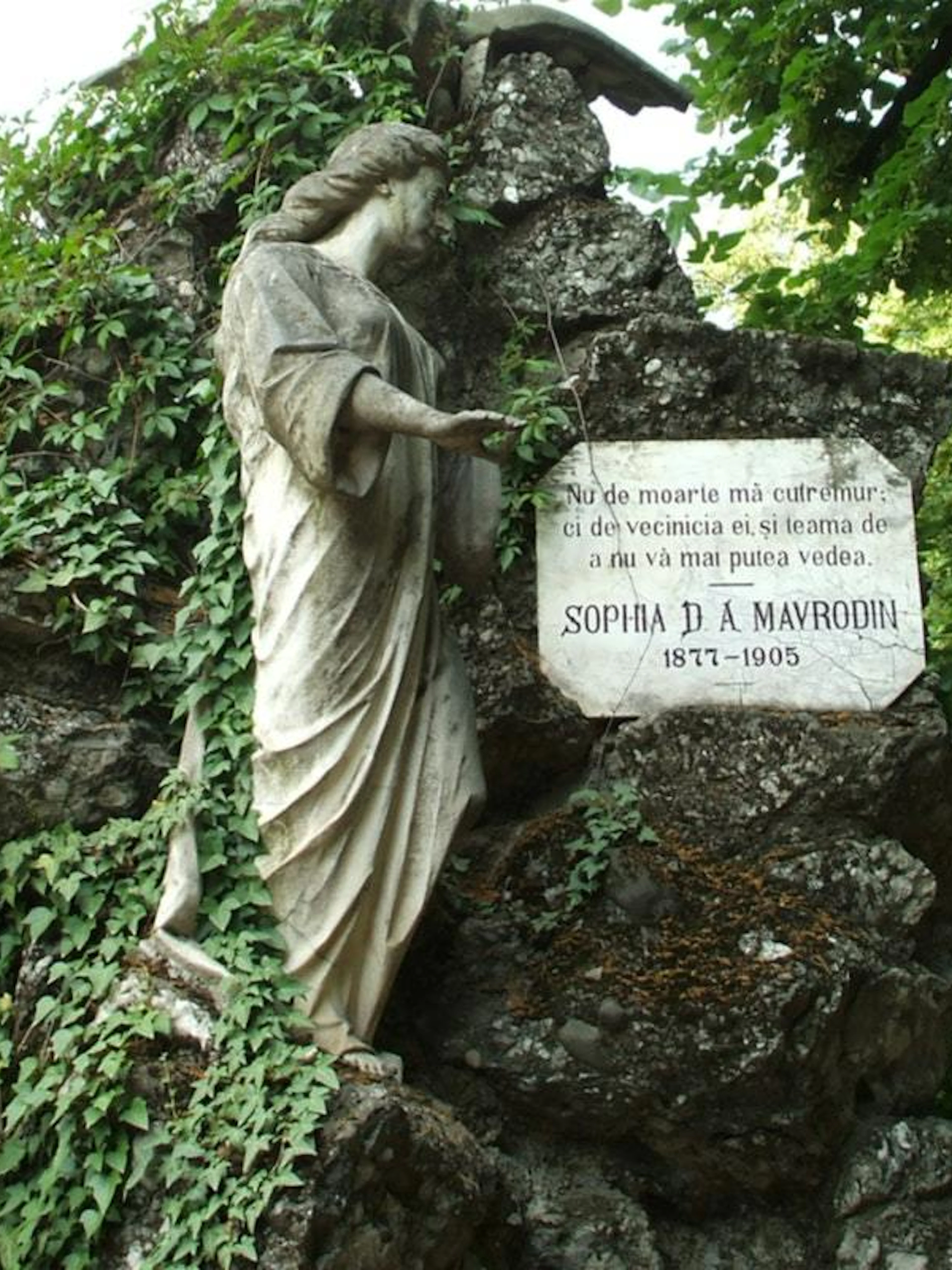 Statue and gravestone of Sophia D. A. Mavrodin at Bellu Cemetery, Bucharest, surrounded by greenery.