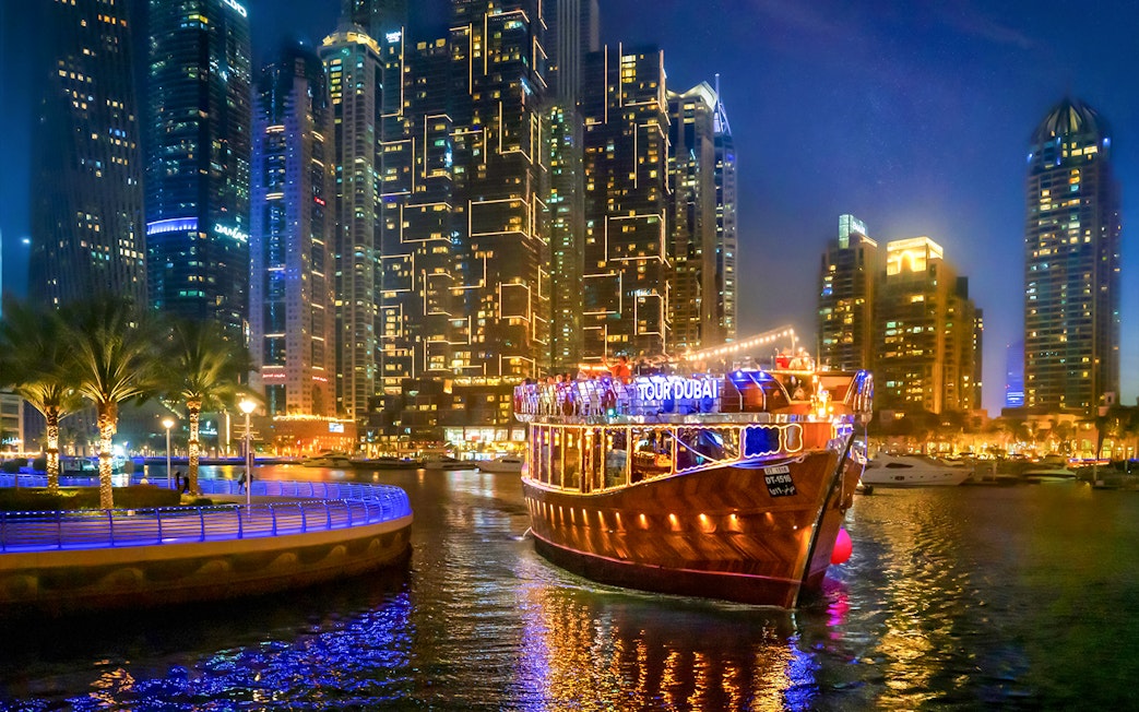 Luxury dhow cruise on Dubai Marina promenade at night with city skyline.