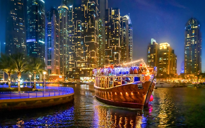 Luxury dhow cruise on Dubai Marina promenade at night with city skyline.