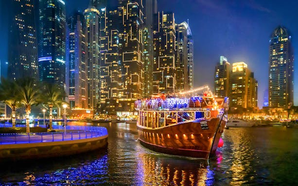 Luxury dhow cruise on Dubai Marina promenade at night with city skyline.