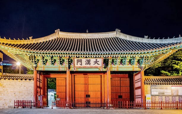 Deoksugung Palace gate illuminated at night, part of Seoul Night Guided Tour.