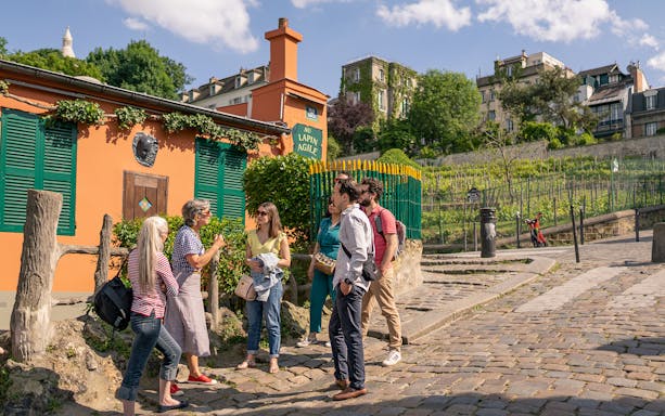 Tourists listening to a guide outside Au Lapin Agile in Montmartre, Paris.