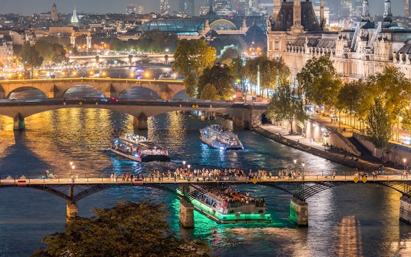 Seine River dinner cruise with live music passing under Paris bridges at night.