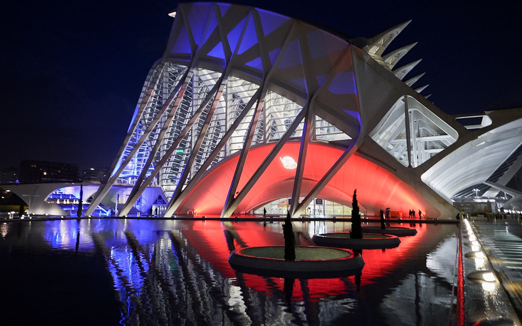 Hemisfèric and Science Museum Valencia illuminated at night, reflecting in water.